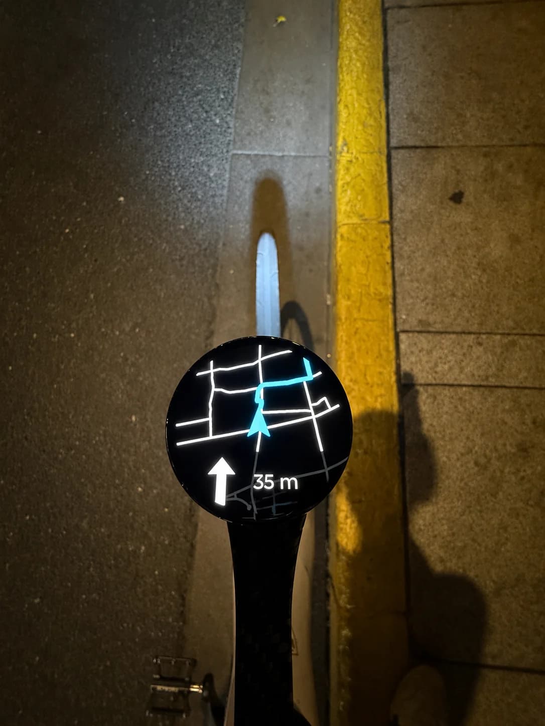 Bicino showing a turn-by-turn route while mounted over a white bike wheel at night